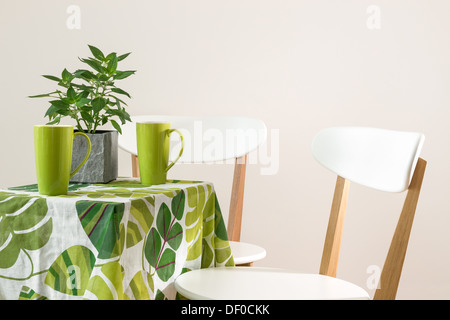 Deux chaises et table lumineuse avec des tasses de thé et de menthe dans une casserole. Banque D'Images