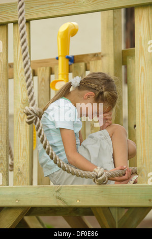 Pleurer 7-year-old girl, blessée au pied de la montée d'une corde sur une aire de jeux Banque D'Images