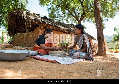 Les femmes village à l'aide de meules pierres pour moudre le mil rouge / Graines Graines Ragi Ragi en farine. L'Andhra Pradesh. L'Inde Banque D'Images