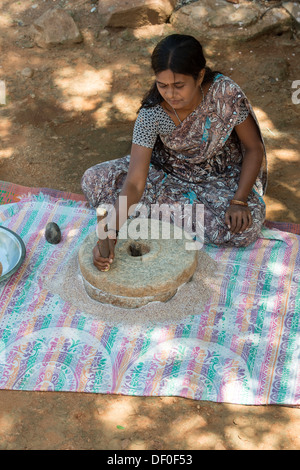 Femme village à l'aide de meules pierres pour moudre le mil rouge / Graines Graines Ragi Ragi en farine. L'Andhra Pradesh. L'Inde Banque D'Images