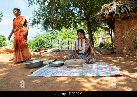 Les femmes village à l'aide de meules pierres pour moudre le mil rouge / Graines Graines Ragi Ragi en farine. L'Andhra Pradesh. L'Inde Banque D'Images