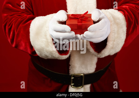 Photo de Père Noël les mains gantées tenant coffret rouge Banque D'Images