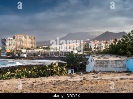 Vieux bâtiments de ferme avec jardin ferme cultivée en premier plan et les bâtiments modernes de Los Cristianos holiday resort en arrière-plan Banque D'Images