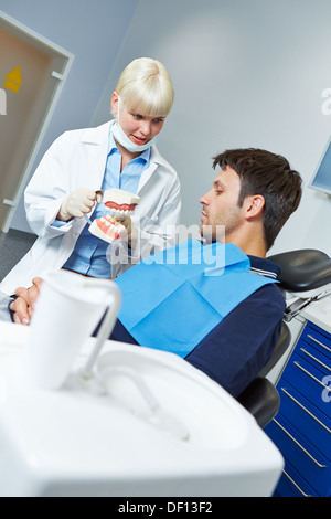 Femme dentiste expliquant les soins dentaires dentiers avec à un patient Banque D'Images