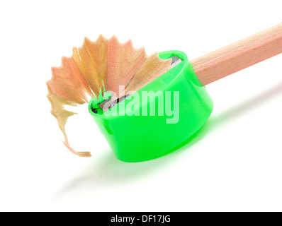 En affinant un crayon dont l'aiguiseur vert isolé sur fond blanc Banque D'Images