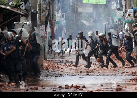 Narayanganj, au Bangladesh. 26 août, 2013. Les fonctionnaires de police du Bangladesh se mettre à couvert, des travailleurs du vêtement jeter des pierres au cours d'une manifestation dans la région de Narayanganj le 26 septembre 2013. La plupart des usines de confection du Bangladesh ont rouvert après cinq jours de manifestations violentes sur les hausses de salaires pour les travailleurs du textile, après que le gouvernement s'est engagé à réprimer les troubles civils 'avec tous vigueur . Banque D'Images