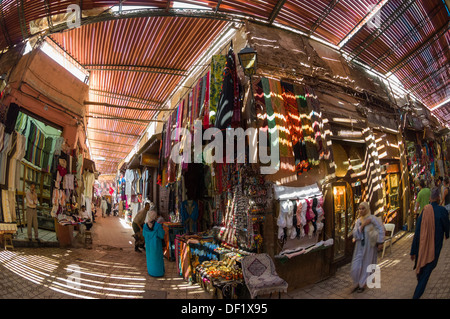 Les toits à lattes illuminant le décrochage, vêtements et les femmes marocaines shopping en costume traditionnel dans un souk local, Marrakech, Maroc Banque D'Images