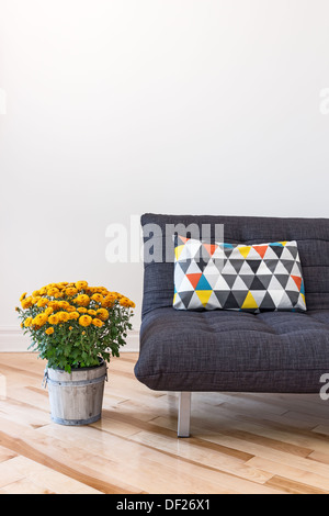 Des chrysanthèmes orange et gris canapé décorés avec un coussin. Banque D'Images