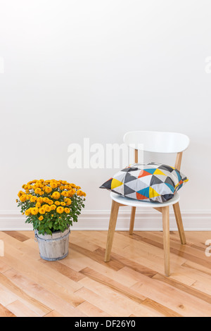 Coussin lumineux sur une chaise, et chrysanthèmes orange décoration d'une chambre. Banque D'Images