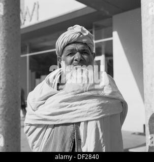 Photo historique de la période 1950 par J Allan Cash d'un homme afghan âgé barbu à Kaboul, en Afghanistan, enveloppé d'une robe traditionnelle en coton ou en tissu autour de lui et d'une barbe et d'une coiffure. Banque D'Images