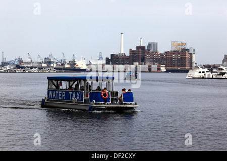 Taxi de l'eau traversant Port intérieur, le bâtiment de l'usine de sucre Domino sur Locust Point en arrière-plan, Baltimore, Maryland, USA Banque D'Images