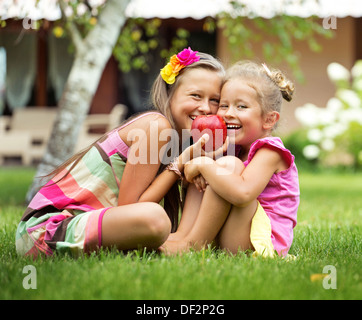 Jolies jeunes soeurs posant avec pomme rouge énorme Banque D'Images