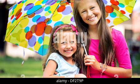 Les jeunes sœurs posant avec parapluie repéré colorés Banque D'Images