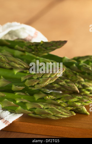 L'asperge verte crue enveloppée dans un torchon posé sur une planche en bois Banque D'Images