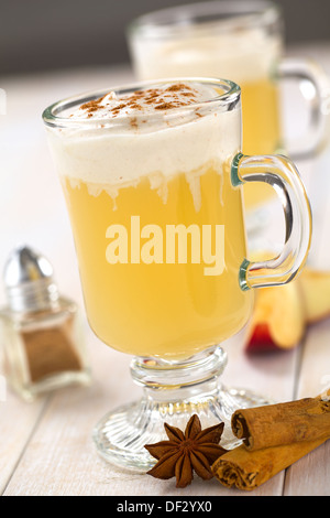 Apple fait chaud maison punch jus de pommes, de gingembre, d'anis et de la cannelle avec de la crème fouettée à la cannelle et la poudre de cannelle sur le dessus Banque D'Images