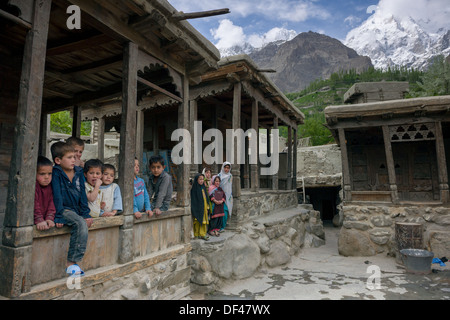 Les enfants dans le vieux carré de Ganish Village, avec des montagnes enneigées derrière, près de Karimabad, Hunza Valley, Gilgit-Baltistan, Pakistan Banque D'Images