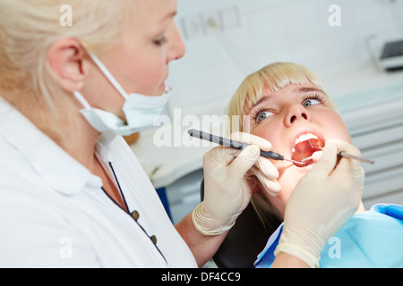 Dentiste examinant female patient avec sonde et miroir Banque D'Images