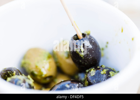 Olives noires et vertes dans un petit bol avec une vinaigrette aux fines herbes et d'huile. L'un est sélectionné d'olive avec une sélection en bois Banque D'Images