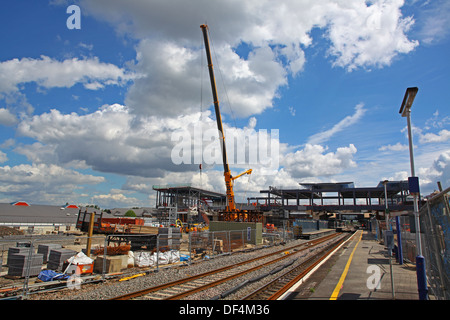 Une grue de levage élevée préparez à soulever une grande section de l'acier dans le nouveau bâtiment de travail autour d'un chemin de fer. Banque D'Images