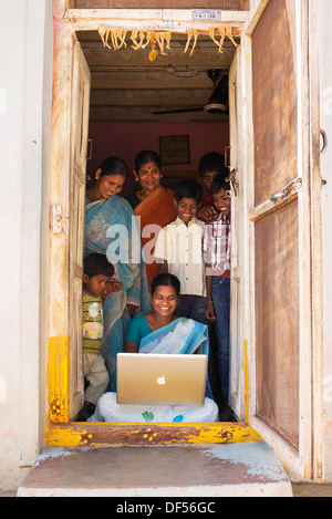 Village de l'Inde rurale et des femmes à la famille à un portable Apple dans sa maison de la porte. L'Andhra Pradesh, Inde Banque D'Images