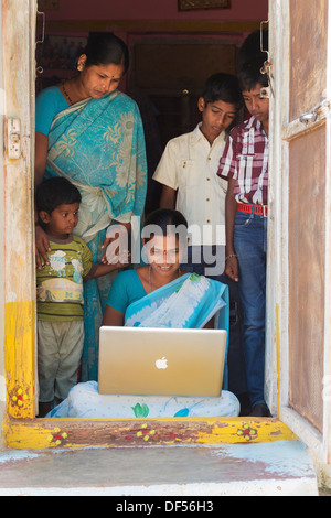 Village de l'Inde rurale et des femmes à la famille à un portable Apple dans sa maison de la porte. L'Andhra Pradesh, Inde Banque D'Images