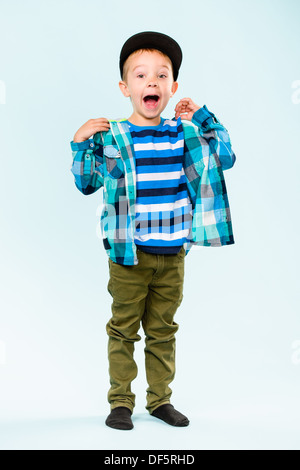 Playful little boy wearing a atteint un sommet en criant sur studio, fond bleu clair Banque D'Images