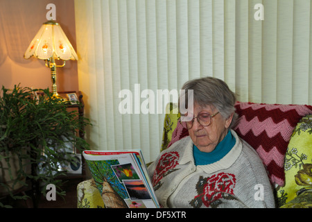 Dame âgée reading magazine dans la salle de séjour-Victoria, Colombie-Britannique, Canada.