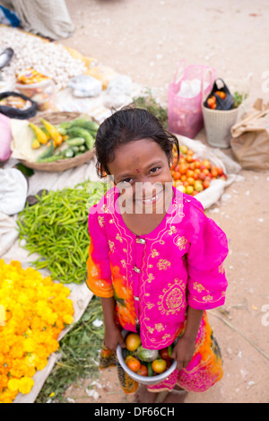 Jeune Indien street girl picking up des légumes dans un marché de rue. L'Andhra Pradesh, Inde Banque D'Images