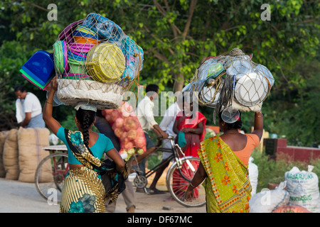 Les femmes indiennes transportant des marchandises sur leur tête au marché. Puttaparthi, Andhra Pradesh, Inde Banque D'Images