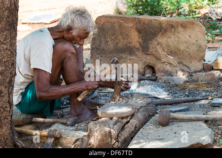 Vieux village de l'Inde rurale homme couper du bois avec une hache. L'Andhra Pradesh, Inde Banque D'Images