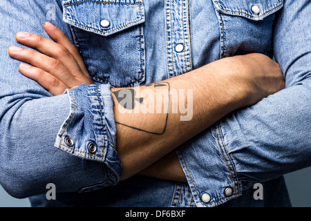 Close up sur le jeune homme, les bras croisés avec ace of spades tattoo Banque D'Images