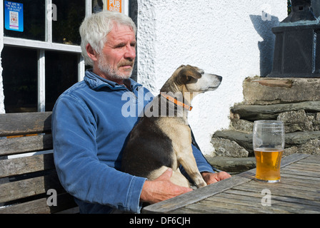 L'homme et le chien à l'extérieur du bras de forgerons, Broughton Mills, Parc National de Lake District, Cumbria, Angleterre, Royaume-Uni Banque D'Images