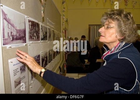 Femme âgée parcourt les vieilles photographies lors d'une journée portes ouvertes de l'histoire du village, east meon, près de petersfield, Hampshire, Royaume-Uni. Banque D'Images