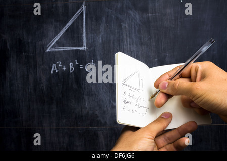 Jeune homme prend des notes du théorème de Pythagore par blackboard Banque D'Images