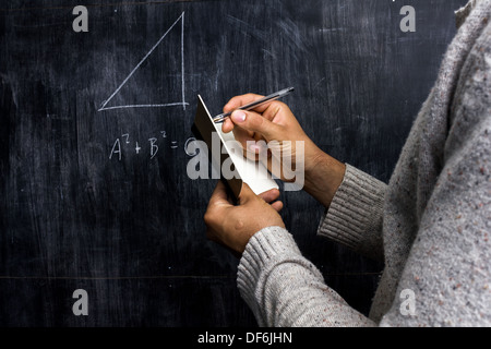Jeune homme en prenant des notes de formule mathématique sur un tableau noir Banque D'Images