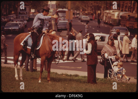 Un policier à cheval patrouille une artère animée du centre-ville, démontrant la présence de forces de l'ordre et de la sécurité publique dans un environnement urbain. Banque D'Images