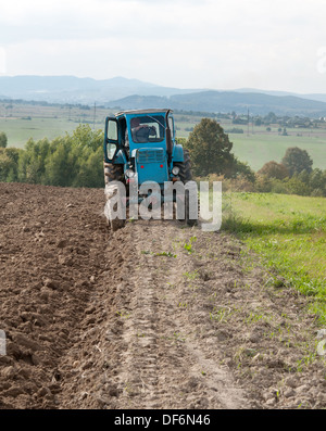 Vieux tracteur bleu en automne sur terrain Banque D'Images