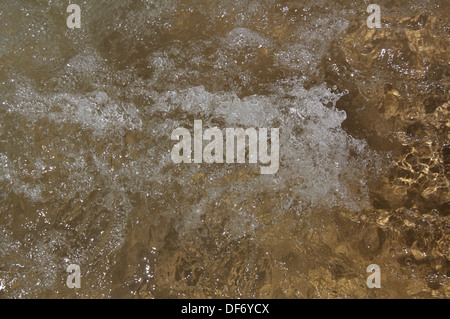 Liquide en écoulement. Fonctionnement de l'eau fraîche Claire plus de cailloux sur un lit de la rivière. La motion gelés par une grande vitesse d'obturation en plein soleil. Banque D'Images
