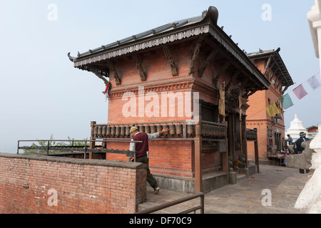 L'homme en tournant les roues de prière au Temple de Swayambhunath (Monkey Temple bouddhiste) - Katmandou, Vallée de Katmandou, Népal, Zone Bagmati Banque D'Images