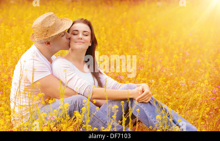 Jeune famille s'embrasser à l'extérieur, assis sur l'herbe sèche au jardin d'automne, de passer du temps ensemble, relation romantique Banque D'Images