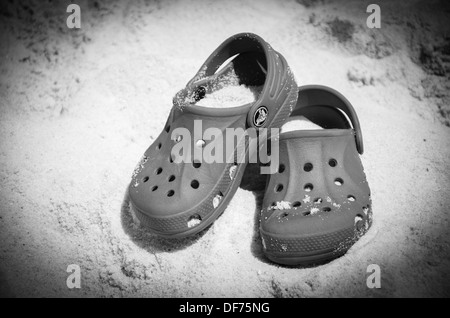 Paire de chaussures Crocs couverts de sable sur la plage Banque D'Images