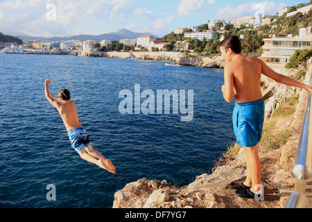 Les adolescents d'un saut d'la plage rocheuse de la Réserve en ville Nice, Côte d'Azur. Banque D'Images