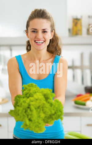 Smiling young woman showing salade fraîche Banque D'Images