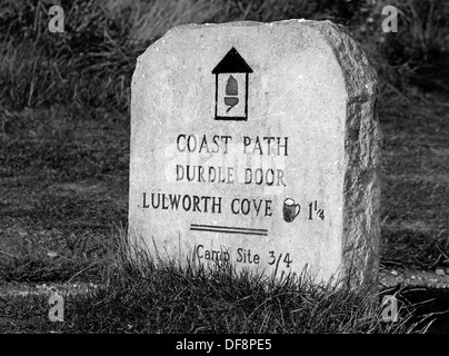 Un vieux sentier en pierre/Route Marker marque la promenade côtière de Lulworth Cove à Durdle Door, Dorset, England, UK. (Noir et blanc) Banque D'Images