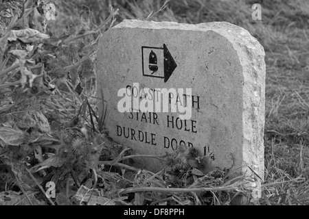 Un vieux sentier en pierre/Route, marqueur marque la promenade côtière de crique de Lulworth Cove à Durdle Door. Dorset, Angleterre, Royaume-Uni (noir et blanc) Banque D'Images