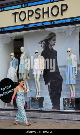 Une jeune femme parlant sur un téléphone mobile comme elle marche par le Topshop store sur Princes Street à Edimbourg. Banque D'Images