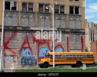 Autobus scolaire jaune par un bâtiment abandonné couvert de graffitis, Detroit, Michigan, USA Banque D'Images