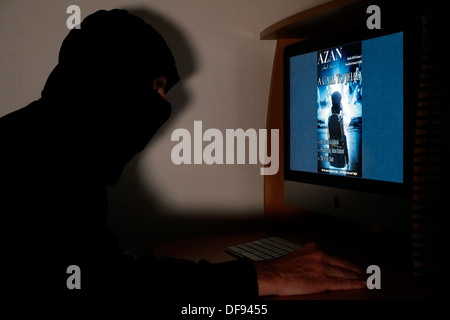 Le phoque à capuchon et à l'homme masqué à la magazine en ligne azan terroristes sur son ordinateur Banque D'Images