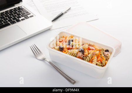 Manger une salade de pâtes aux légumes et thon dans le bureau Banque D'Images