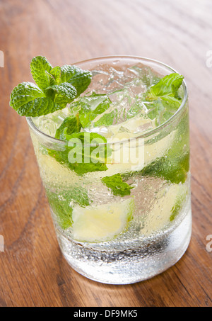 Le Mojito servi dans un verre de glace pilée et de la chaux sur table en bois Banque D'Images